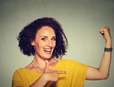 Closeup portrait fit middle aged healthy model woman flexing muscles confident showing her strength isolated on gray background. Positive emotion faci