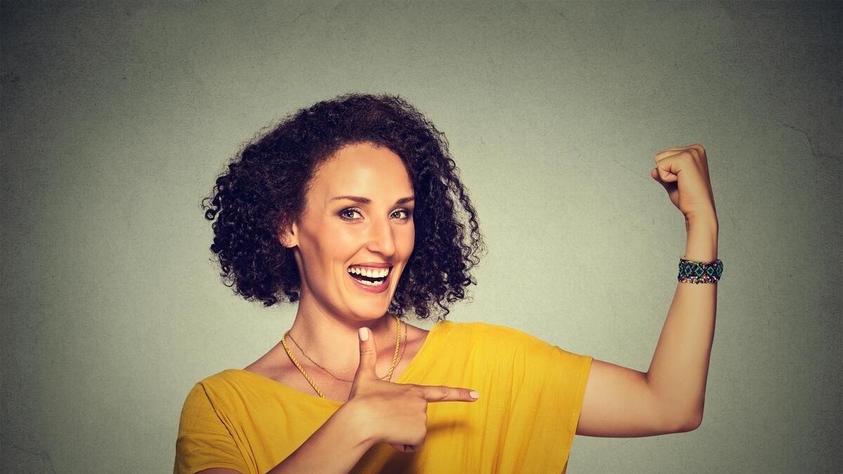 Closeup portrait fit middle aged healthy model woman flexing muscles confident showing her strength isolated on gray background. Positive emotion faci